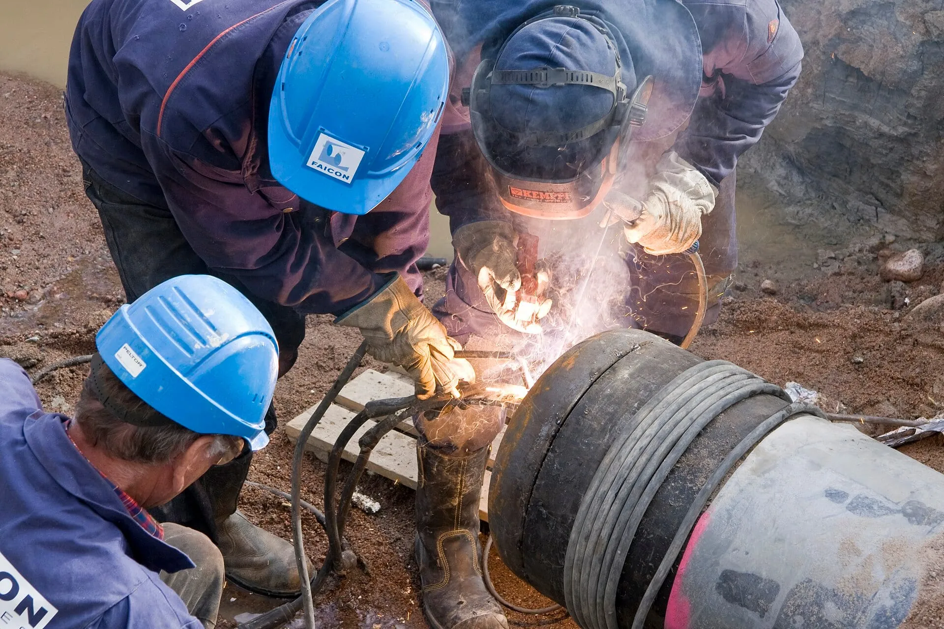 Welders joining a pipe section