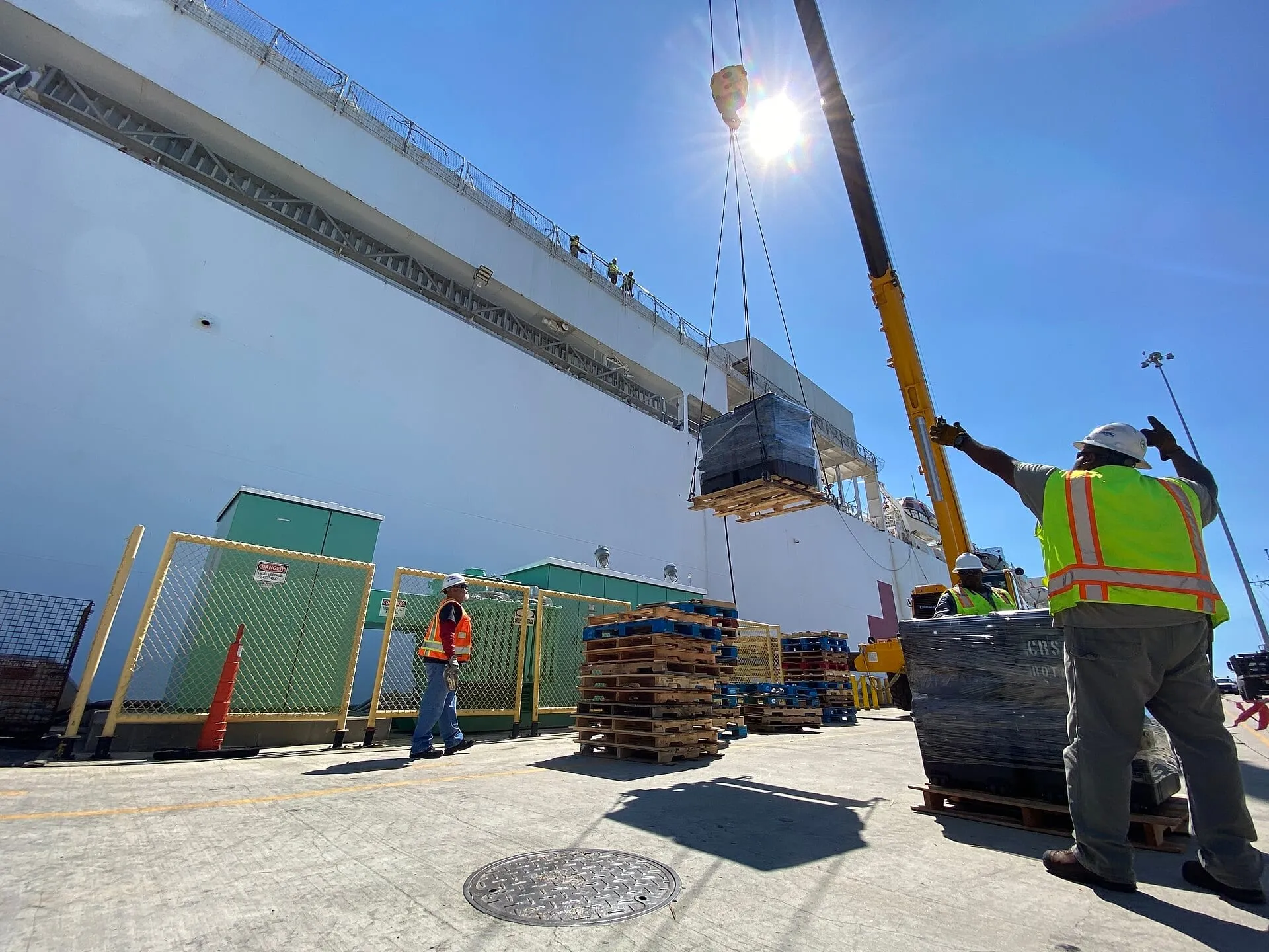 Dock workers guiding a crane lift on the quay